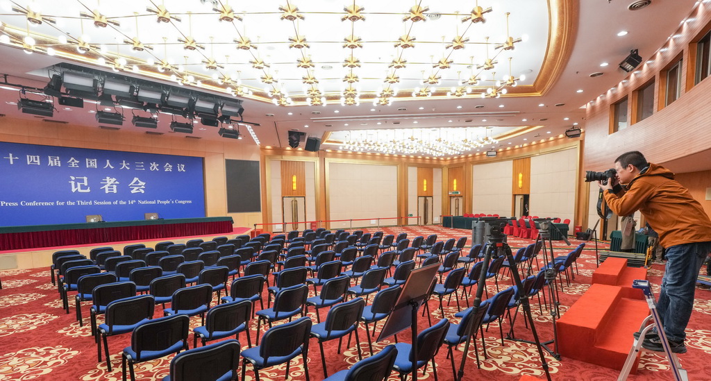 2月27日，一名記者在全國兩會新聞中心新聞發布廳拍攝。