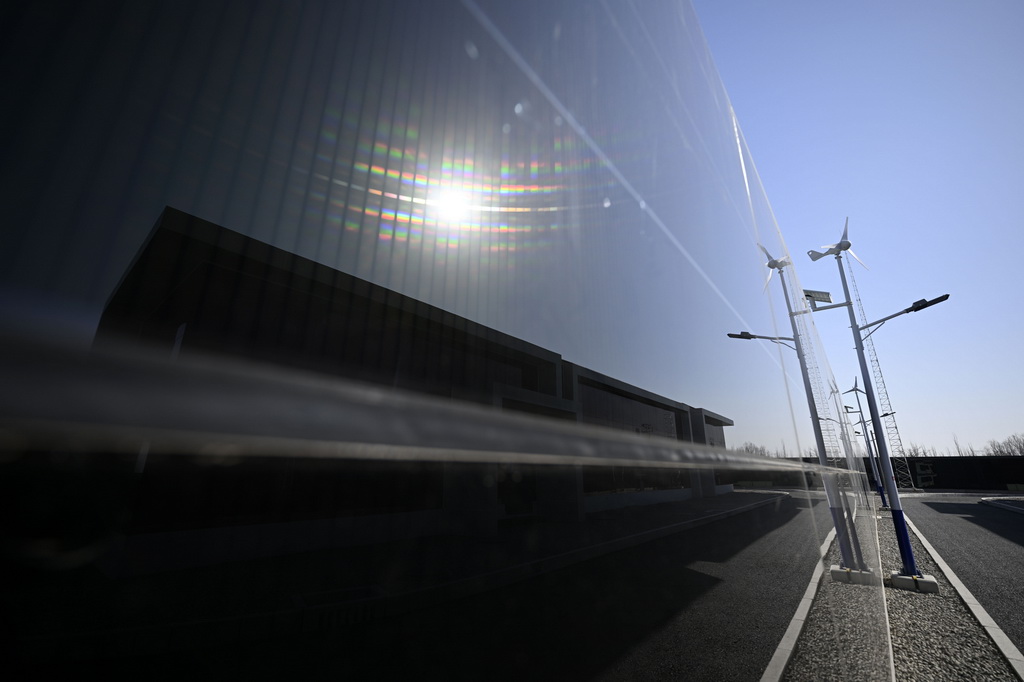 圖為2月27日在寧夏銀川原隆110千伏變電站內拍攝的碲化鎘發電玻璃光伏組件圍墻與小型風力發電機。
