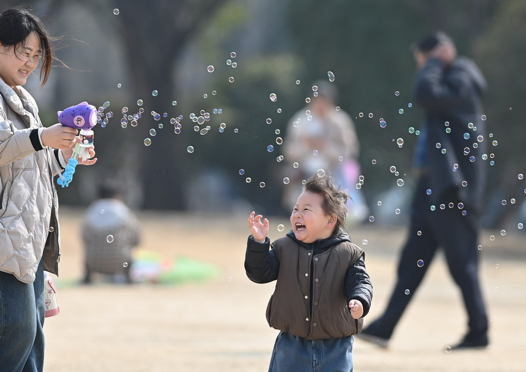 3月9日，家長和孩子在山東省滕州市一處公園玩泡泡。新華社發（李志軍攝）