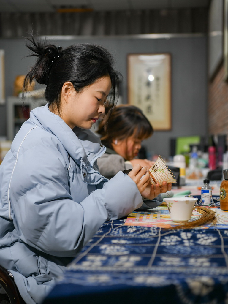 白梓憶（前）在編制“熊貓抱竹”蓋碗茶杯（3月7日攝）。新華社記者 王曦 攝