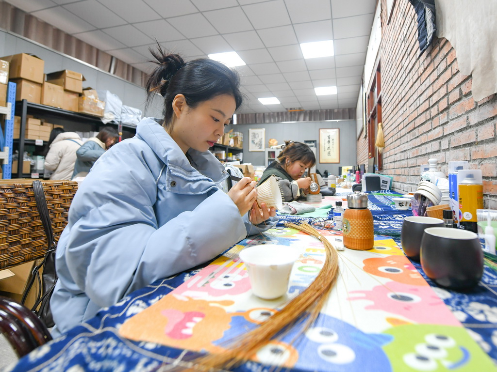白梓憶（前）在編制“熊貓抱竹”蓋碗茶杯（3月7日攝）。新華社記者 王曦 攝