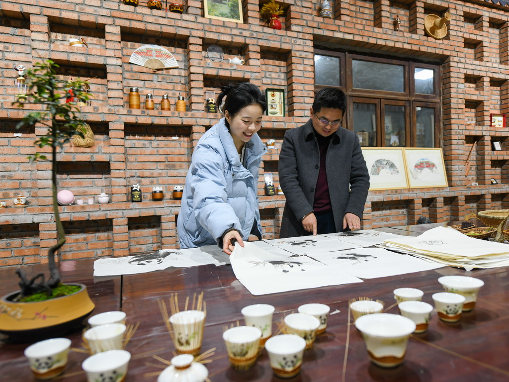 在崇州市朱利原鄉非遺文化園，白靜波和女兒白梓憶在查看“熊貓抱竹”設計草圖（3月7日攝）。新華社記者 王曦 攝