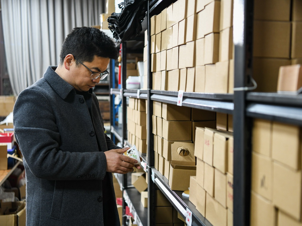 白靜波在庫房查看即將入庫的“熊貓抱竹”蓋碗茶杯成品（3月7日攝）。新華社記者 王曦 攝