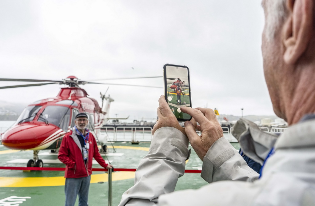 3月18日，在?？啃挛魈m克賴斯特徹奇市利特爾頓港的“雪龍2”號上，參觀者與直升機合影。新華社發（陳思雨蒙攝）