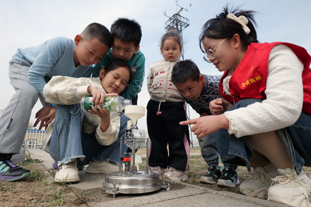 3月23日，山東省濱州市惠民縣桑落墅鎮的孩子們在當地氣象局了解雨量計的工作原理。新華社發（王軍 攝）
