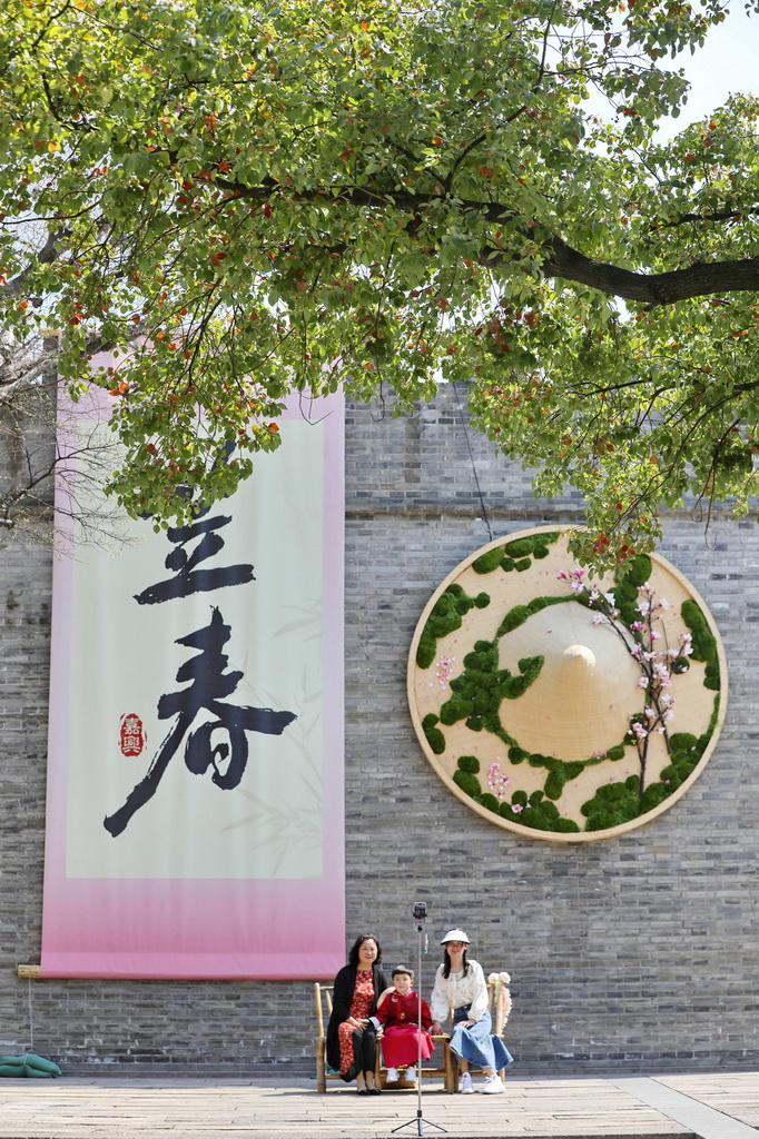 3月22日，在浙江省嘉興市南湖區子城遺址公園，游人在古城墻巨型“笠春”“斗笠”創意裝飾前拍照。新華社發（金鵬攝）