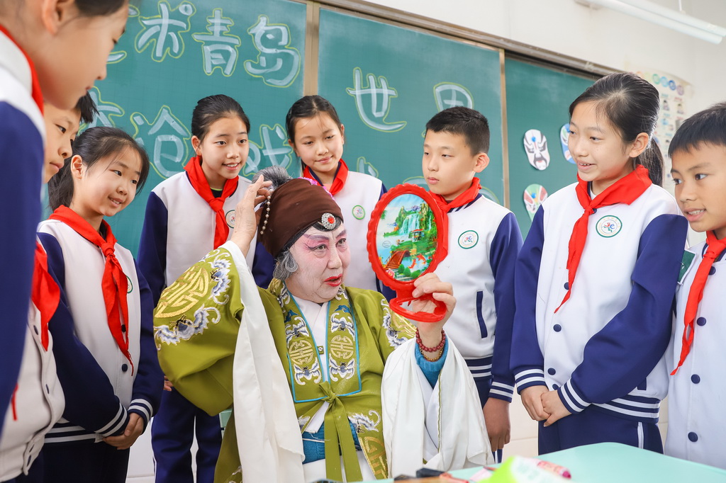 3月25日，在山東青島北山小學開展的“藝術青島·李滄有戲”主題活動中，柳腔演員向學生展示戲曲臉譜繪制。新華社發（張鷹攝）