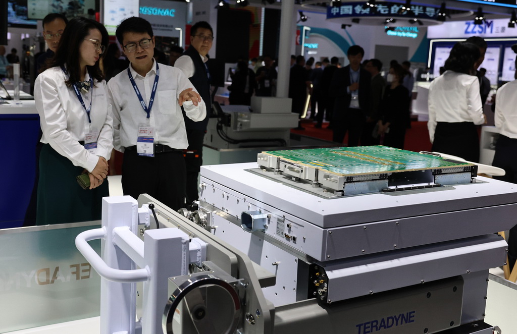 3月26日，參觀者在一個集成電路自動化測試設備展品旁討論交流。