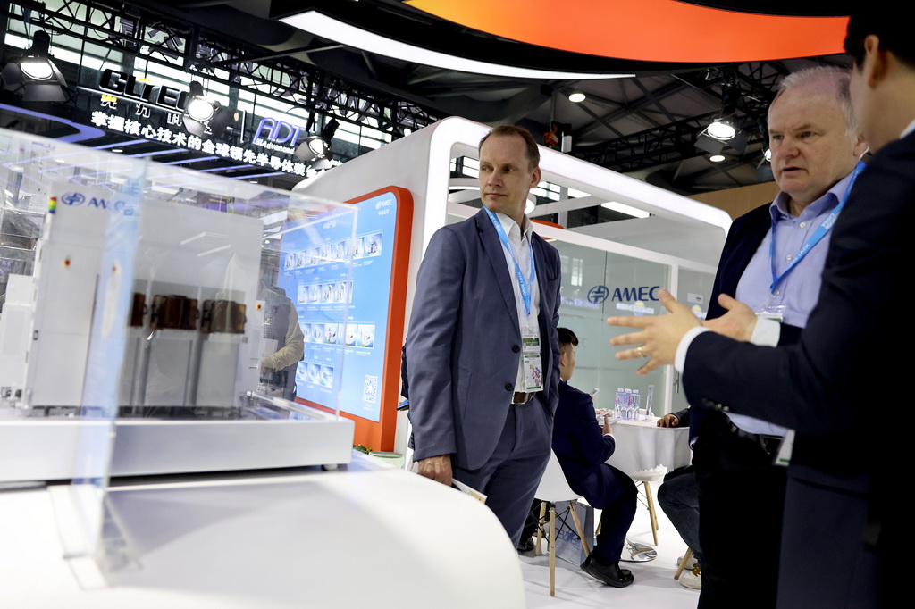 3月26日，參觀者在一組刻蝕機模型展品旁交流討論。