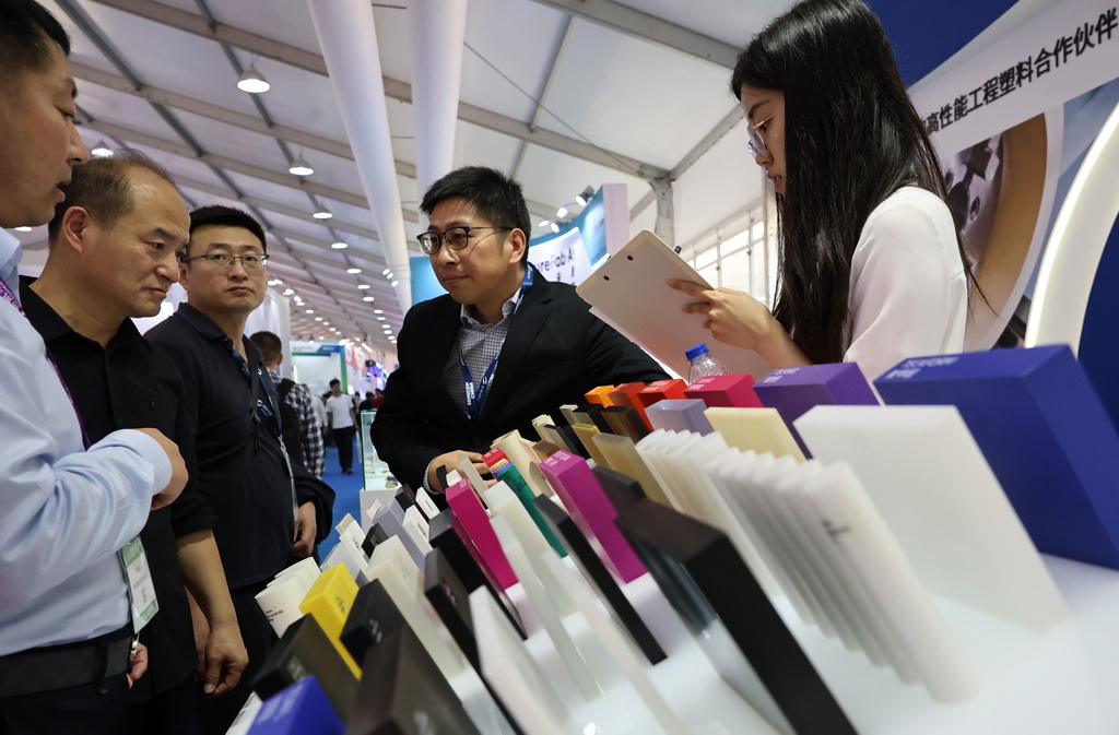 3月26日，參觀者在一組高性能工程塑料展品前交流討論。