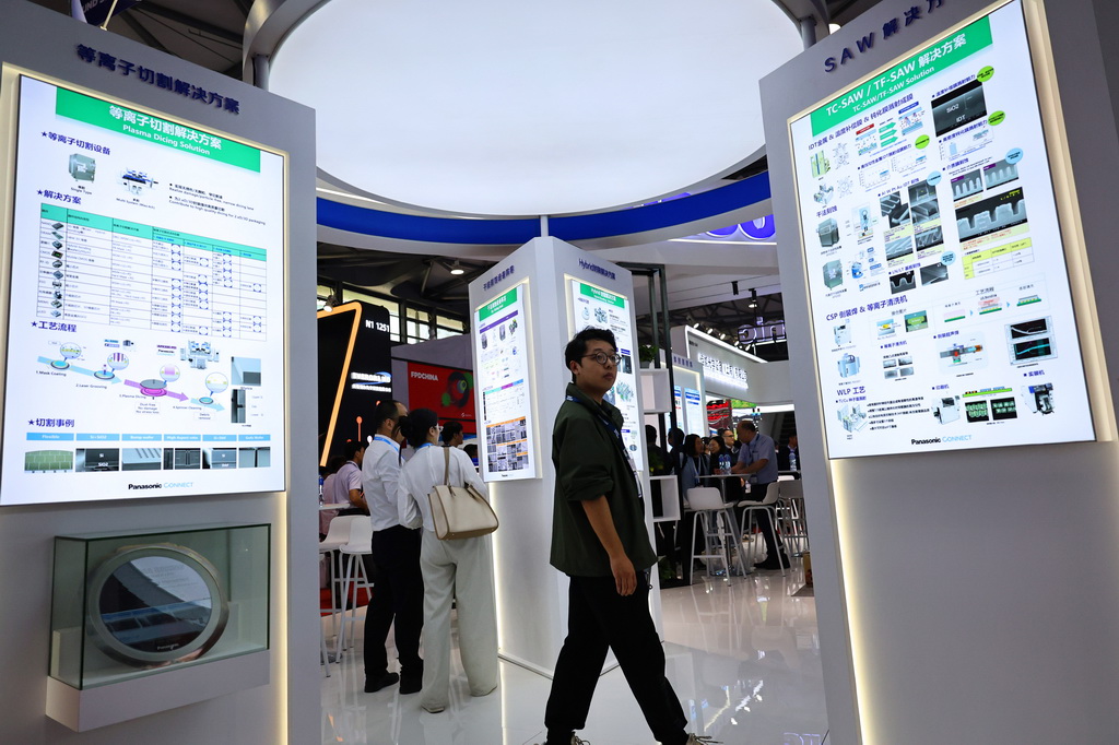 3月26日，參觀者從一個芯片制造技術展示板旁走過。