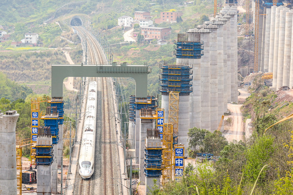 3月27日，鄭渝高鐵線上一列動車從門式墩鋼橫梁下通過。新華社發（黃茂程攝）