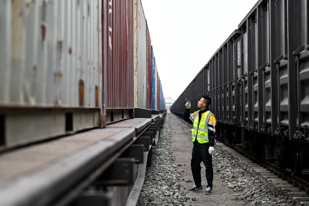 4月3日，在呼和浩特市新暢鐵路專用線，工作人員在巡檢鐵海聯運“一單制”運輸專列上的集裝箱。