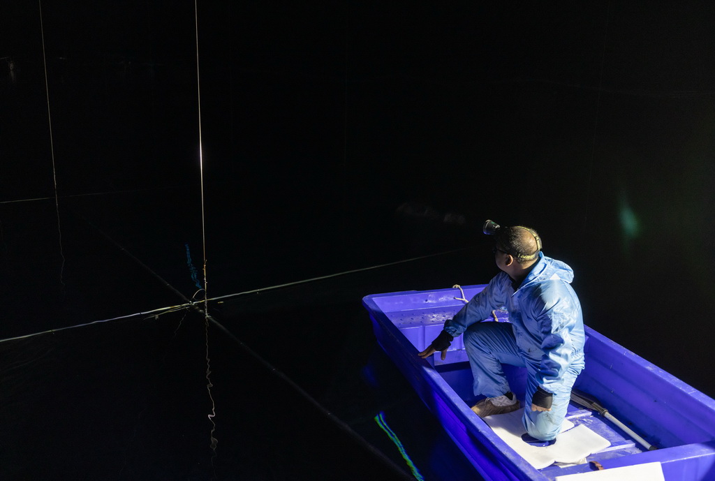 在位于四川省稻城縣海子山的高海拔宇宙線觀測站“拉索”水切倫科夫探測器陣列水池，科研人員坐船更換實驗設備（2023年4月21日攝）。新華社記者 金立旺 攝