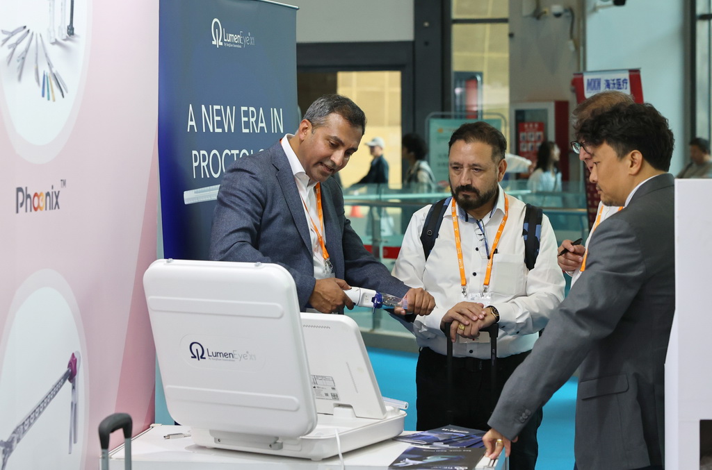 4月8日，一名展商工作人員（左）在向參觀者介紹電動吻合器產品。