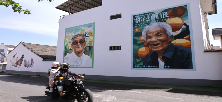 游客在西安市鄠邑區蔡家坡村騎行游玩，村中的特色墻畫引人注目。郝雨辰一攝