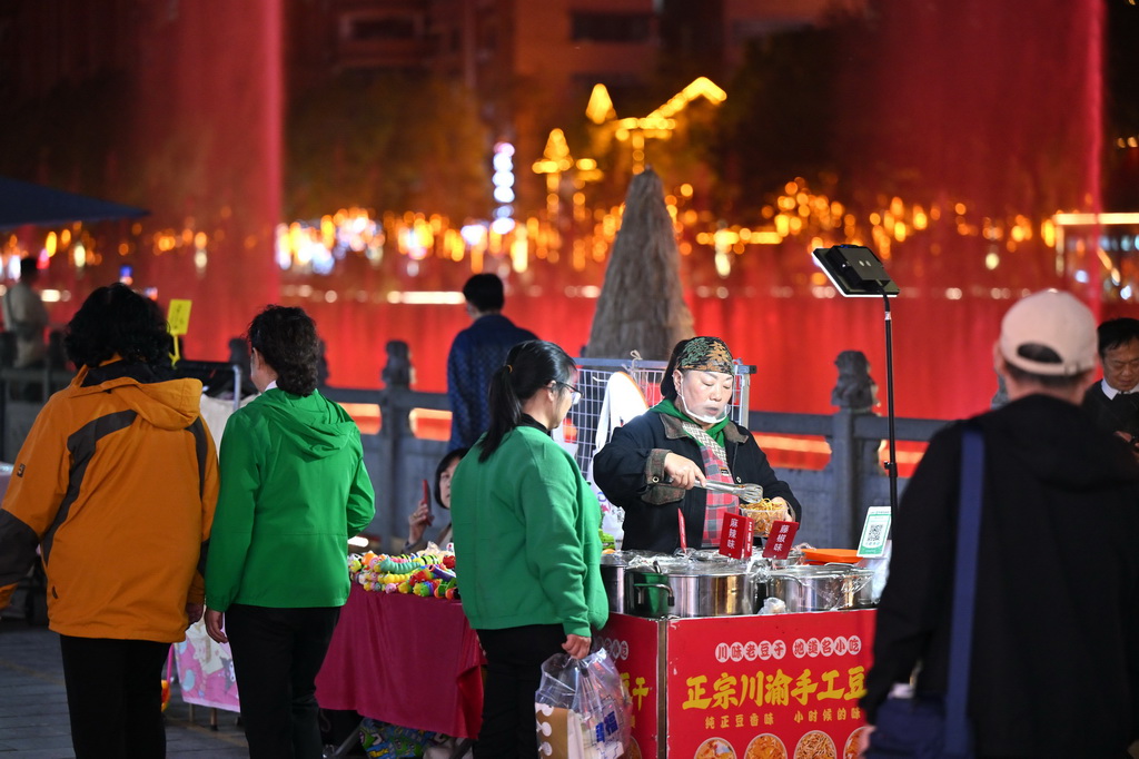 4月12日，攤主在宣恩縣城貢水河畔擺地攤。