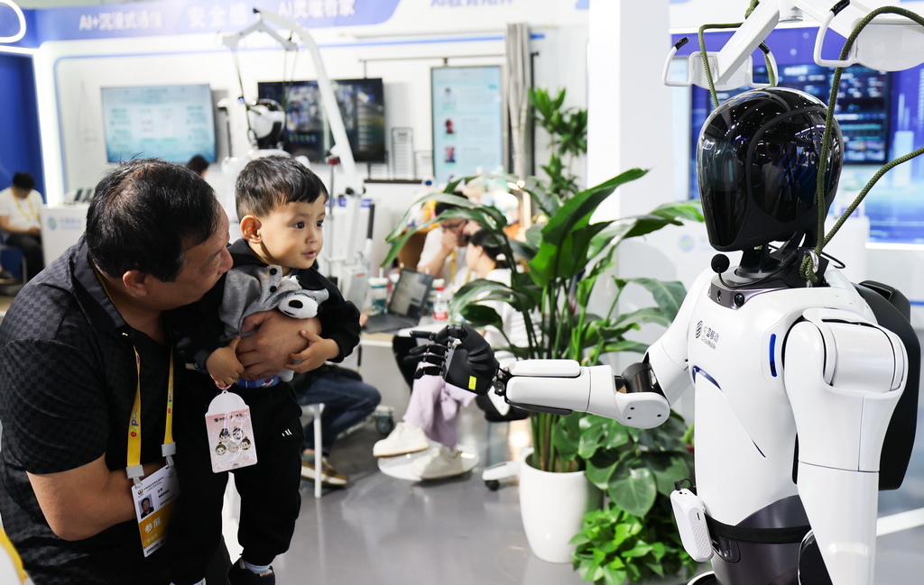 4月14日，在第五屆消博會上，小朋友與中國移動展出的機器人互動。新華社記者 楊冠宇 攝