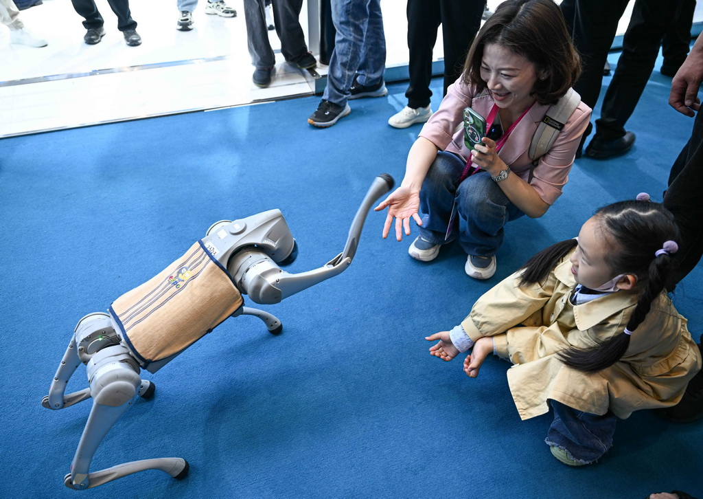 4月14日，觀眾在第五屆消博會宇樹科技展臺與機器狗握手。新華社記者 蒲曉旭 攝