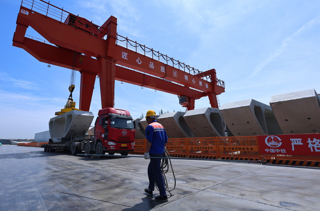 4月16日，工人從隧道弧形件吊裝現場走過。