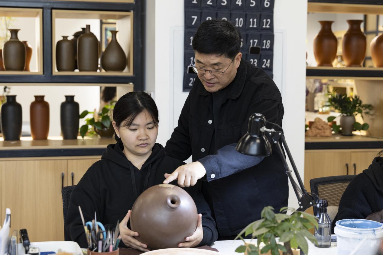 榮縣土陶創意園首席藝術家劉勇（右）在指導學生創作。王劍攝