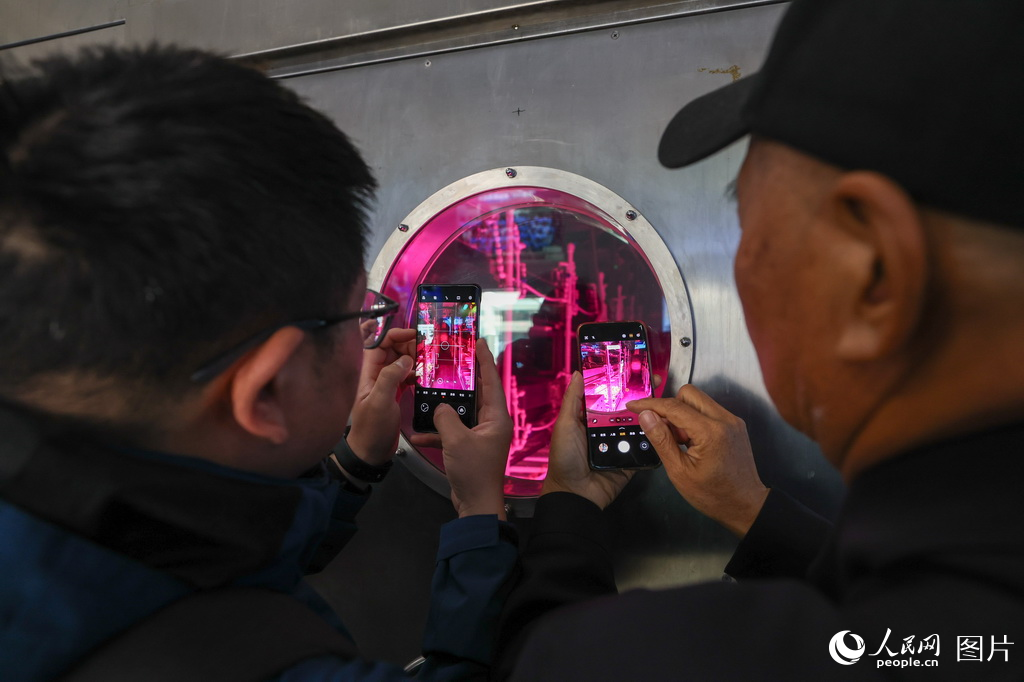 觀眾在“月宮一號”科普基地植物艙窗口前拍照參觀。