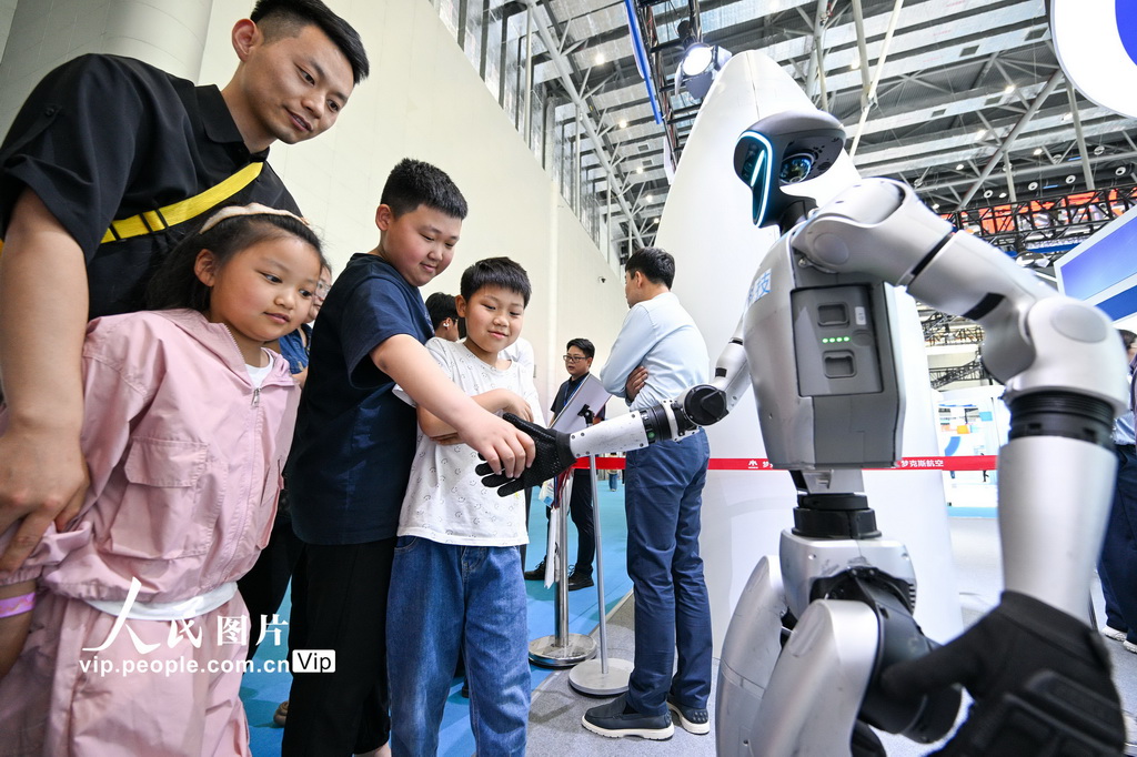 4月26日，小朋友在第三屆中國（安徽）科技創新成果轉化交易會上跟機器人握手。