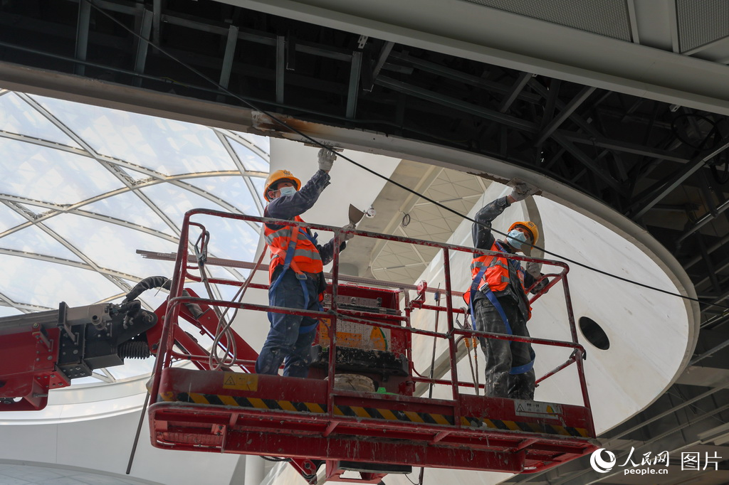 工人在施工現場粉刷樞紐主體結構屋頂。