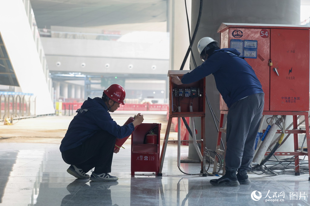 施工人員在現場檢查滅火器、配電箱等裝置，確保施工安全。