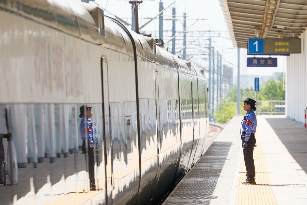5月1日，在江蘇海安站站臺上，客運值班員立崗送車。新華社發（顧彬斌攝）