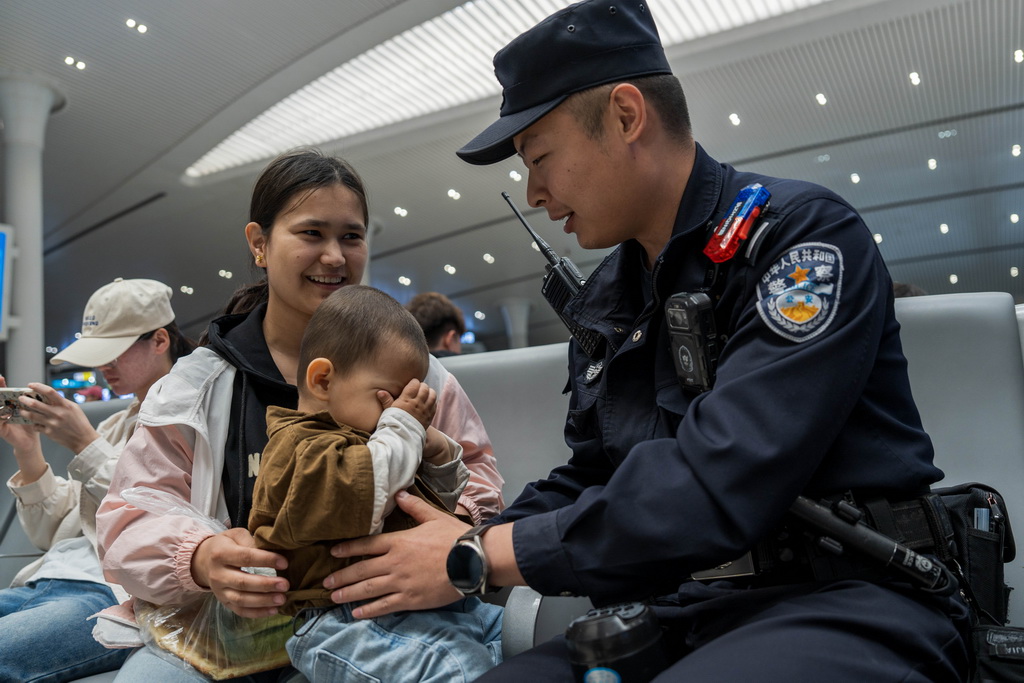 5月1日，烏魯木齊鐵路公安處烏魯木齊站派出所民警向帶小孩的旅客提示乘車安全。新華社發（葉帥 攝）