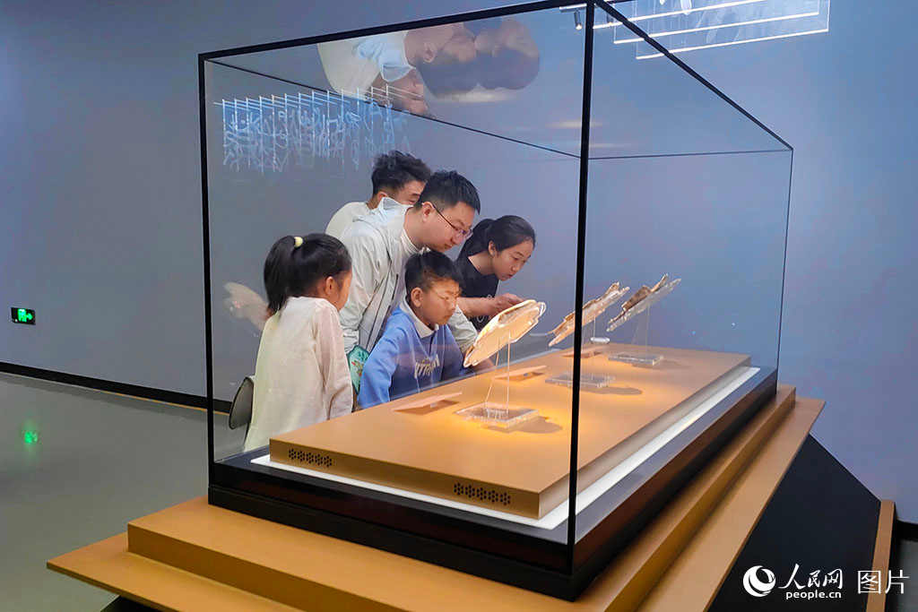2025年5月3日，河南安陽殷墟博物館內，游客駐足在甲骨文展區。3000年前的龜甲歷經歲月打磨，仍清晰可見蒼勁的刻痕，游客透過這些承載著文明密碼的古老文字，仿佛能看到祭祀的盛大場景，真切觸摸到華夏文明傳承的脈絡，感受著中華文化穿越千年的強大生命力。人民網記者 單芳攝