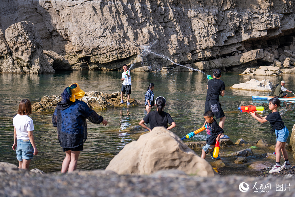 2025年5月2日，貴州省安順市普定縣貓洞村三岔河的淺灘處，游客在戲水嬉戲。人民網記者 涂敏攝