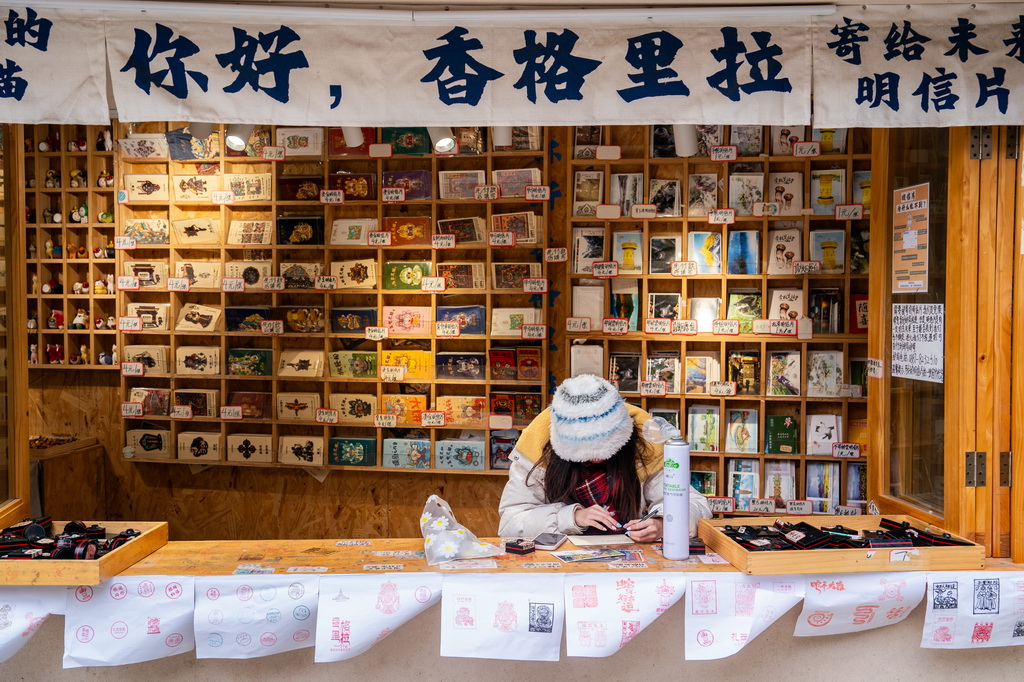 一名游客在云南省迪慶州香格里拉市獨克宗古城寫明信片（2025年3月7日攝）。