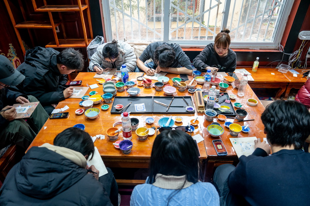 在云南省迪慶州香格里拉市獨克宗古城金龍社區非遺體驗中心，游客體驗繪制唐卡（2025年3月6日攝）。