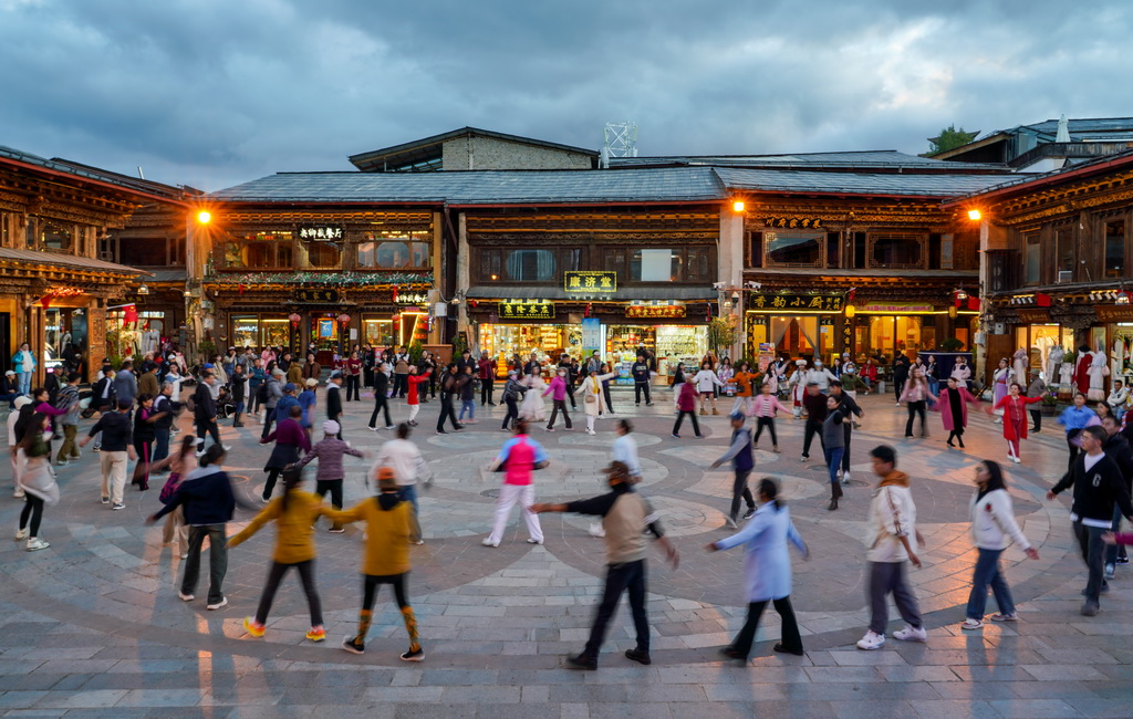 游客和當地群眾在云南省迪慶州香格里拉市獨克宗古城里一起跳舞（2024年9月27日攝）。