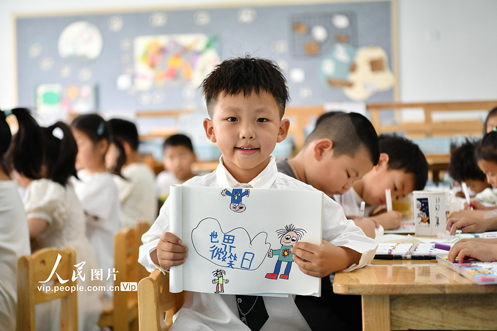 2025年5月7日，安徽省阜陽市阜南縣駱寨社區幼兒園的孩子展示自己繪制心中的笑臉。呂乃明攝（人民圖片網）