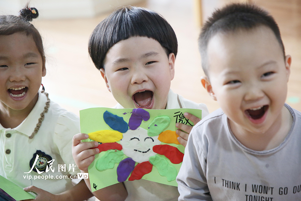 2025年5月7日，山東泰安，泰山華成幼兒園的小朋友展示自己制作彩泥笑臉。陳陽攝（人民圖片網）