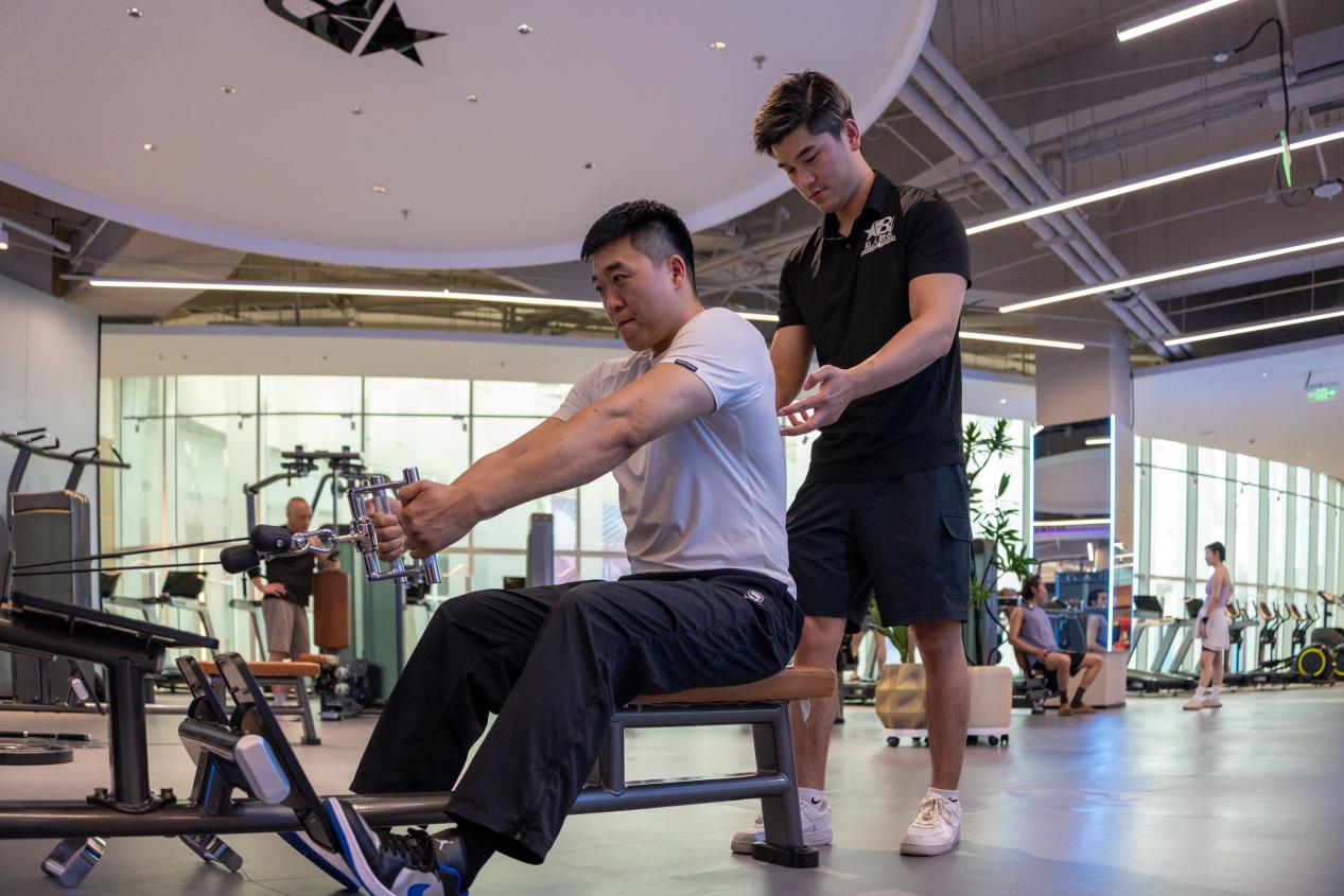 通州遠洋樂堤港健身房內，健身教練在指導訓練。樊利濤攝