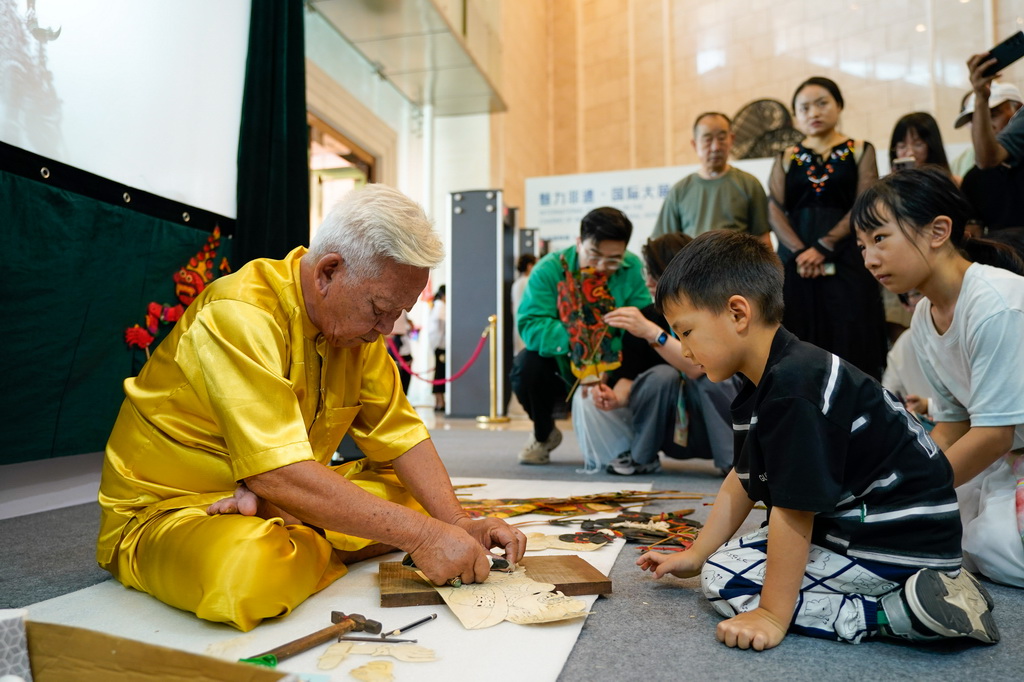 5月28日，在成都國際非遺節主賓國馬來西亞展區，小朋友觀看手藝人制作馬來西亞皮影。