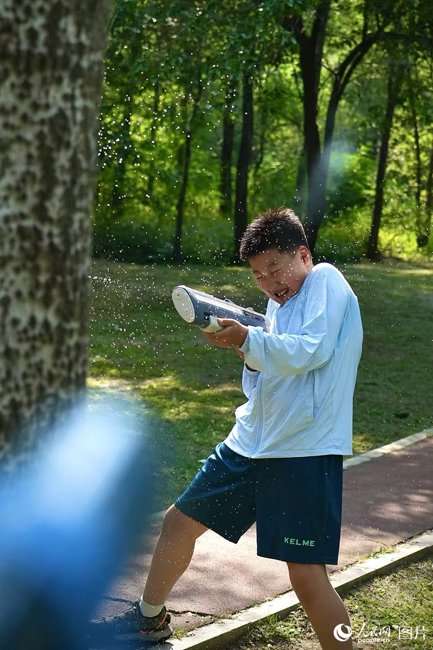 2025年5月29日，夏日炎炎，在遼寧省沈陽市沈河區體院公園的草地上，小朋友們正在進行一場酣暢淋漓的水槍大戰。人民網記者 周頌雪攝