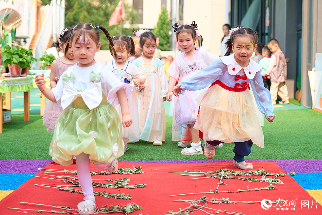 2025年5月30日，山西省太原市，孩子們用腳踩艾葉的方式喜迎端午六一雙節。人民網 張超寧攝
