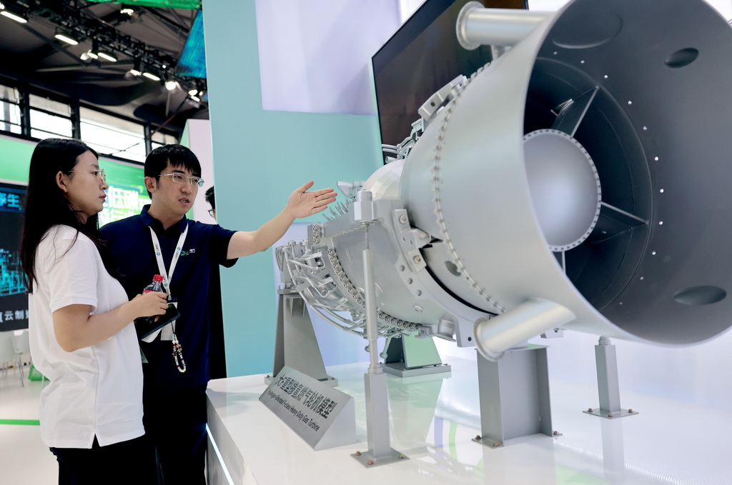 6月5日，工作人員（右）在一個重型摻氫燃氣輪機模型旁向參觀者做介紹。