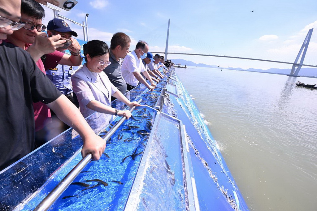 6月6日，在福建省福州市閩江入?？谂e行的全國水生生物同步增殖放流主會場活動中，嘉賓在投放魚苗。
