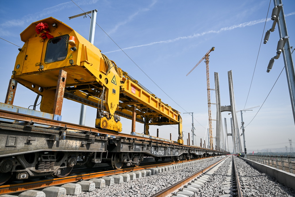 6月6日，在包銀高鐵烏海黃河特大橋，工人操作工程機械進行鋪軌作業。新華社記者 連振 攝