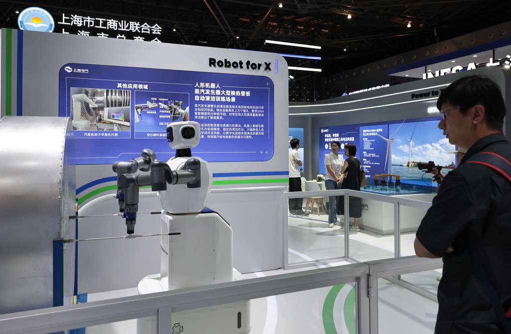 6月11日，參觀者在一個進行作業演示的人形清潔機器人旁駐足觀看。