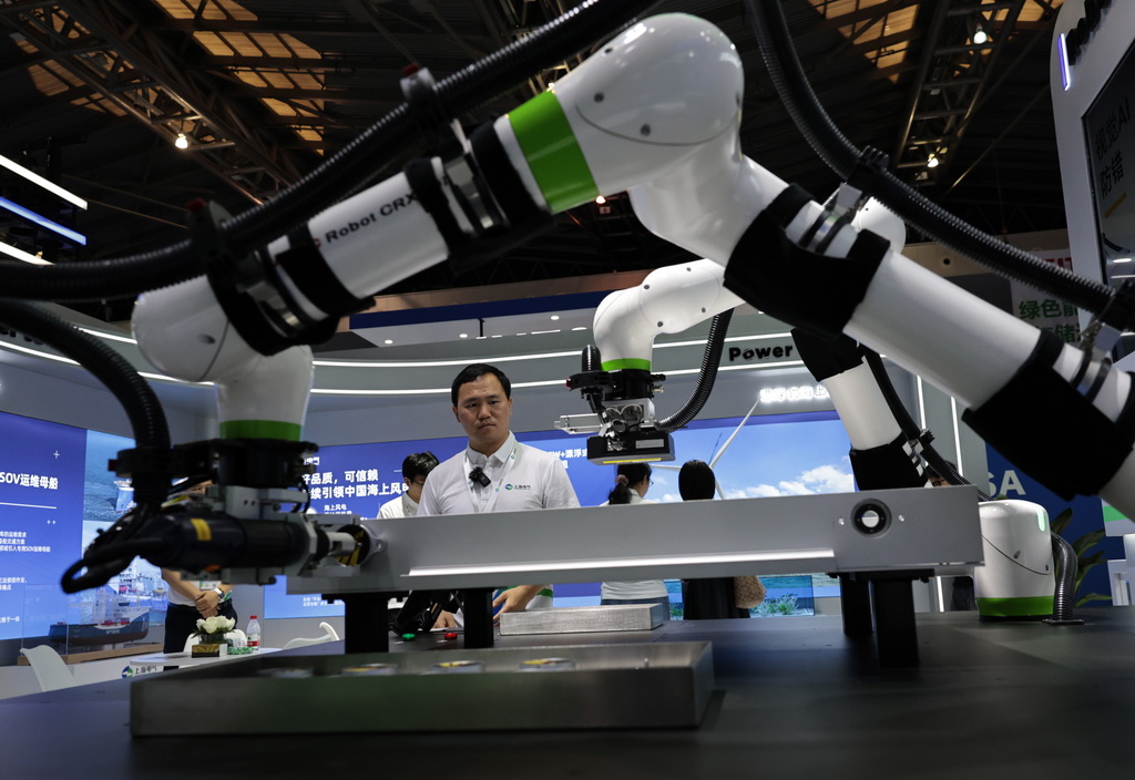 6月11日，工作人員在觀看進行作業演示的電池包裝配及插線檢測協作機器人。