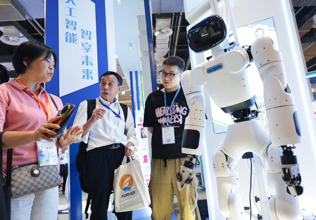6月11日，參觀者在一個人形機器人旁交流討論。