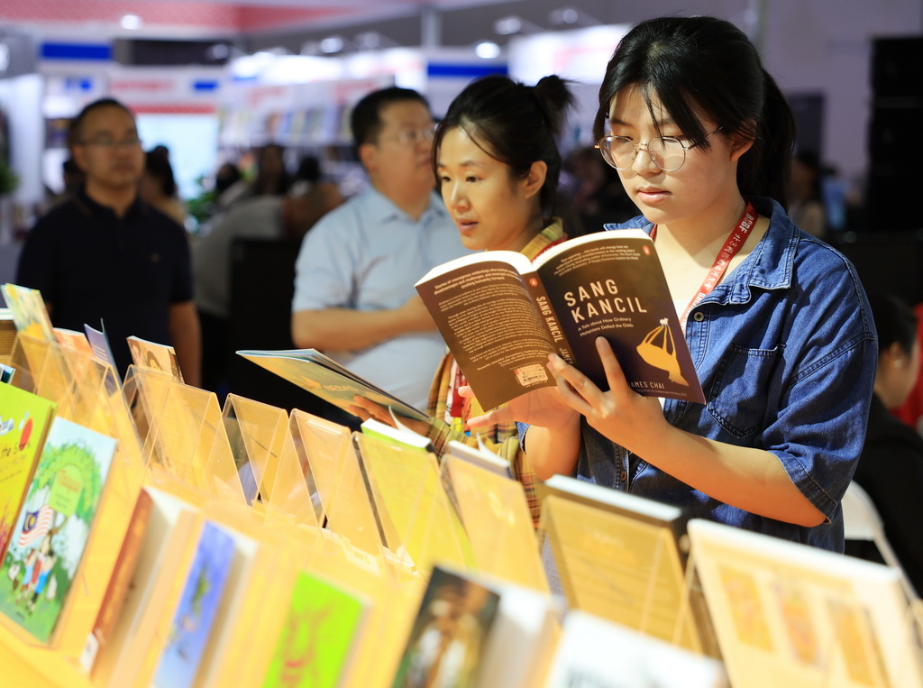 6月18日，觀眾在翻閱主賓國馬來西亞展區的圖書。