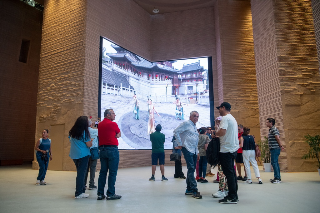 6月24日，游客在大足石刻景區觀賞數字影片。